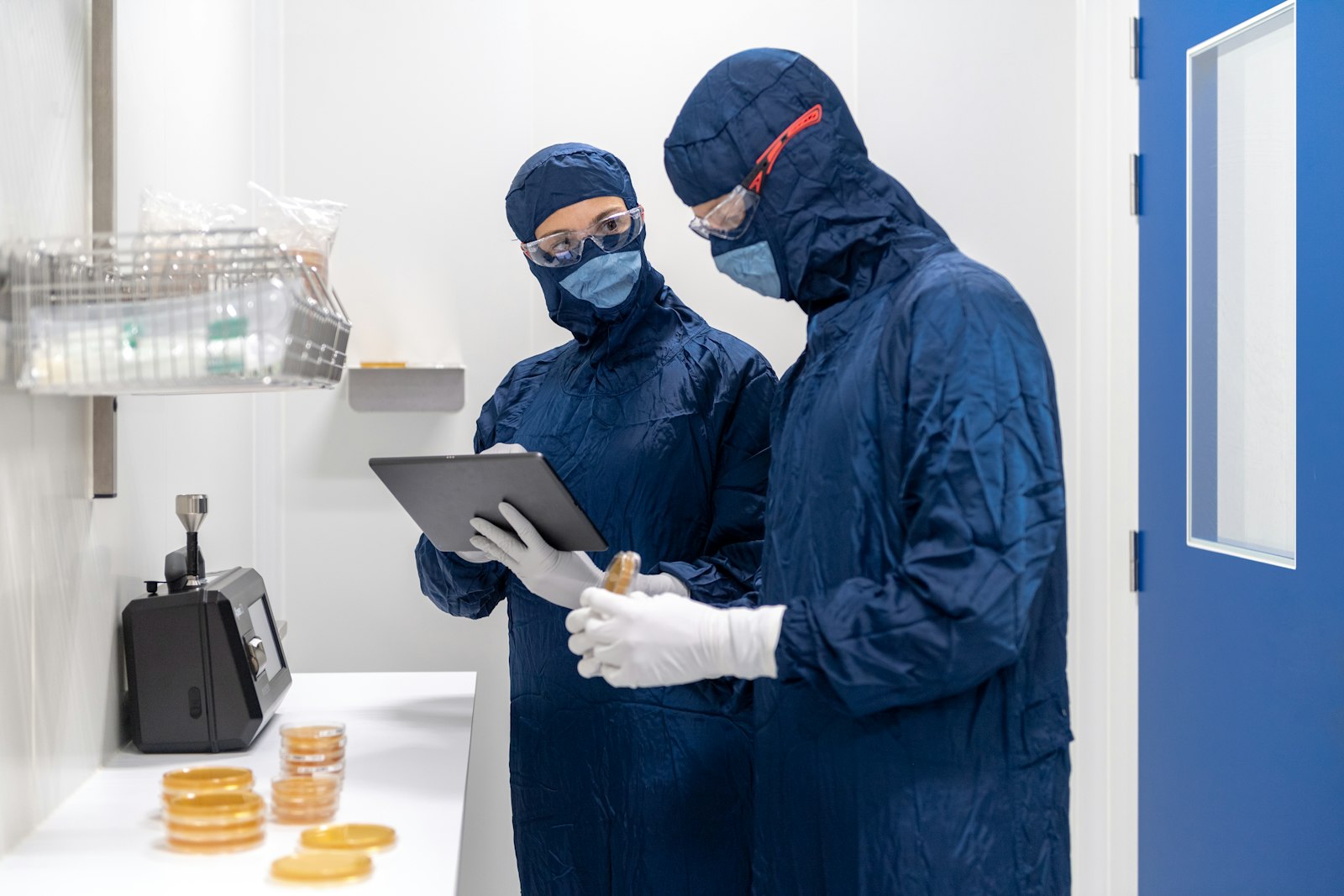 Two pharma cleanroom staff reviewing data on a tablet